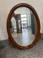 Full front view of oval mirror leaning against wall