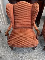 Front view of wingback armchair showing upholstery pattern, rolled arms and front legs
