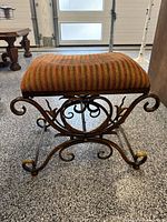 Side view of vanity stool showing striped seat and scroll iron base