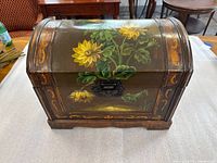 Front view of box showing sunflower painting, dome shape and latch