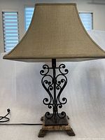 Full view of table lamp showing shade, iron scrollwork, marble base and power cord