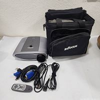 Projector with remote and cables beside open case
