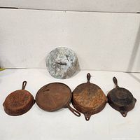 Front view of four skillets and lid