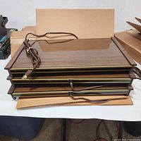 Stack of three warming trays showing wood-grain tops, power cords