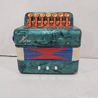 Front view showing brand name, 10 orange keys, 2 white buttons, bellows pattern and logo text