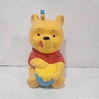 Front view of ceramic Winnie the Pooh cookie jar showing honey pot and lid