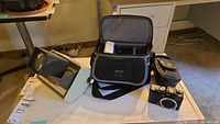 Lot overview showing Arhus slide viewer, Denali camera bag, leather pouch, Canon camera