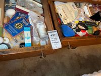 Two open drawers showing assorted household items including candles box, Sam Adams coasters, tools