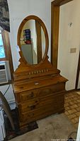 Front view of knotty pine dresser with oval mirror attached, showing drawers and overall form