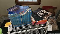 Overall lot on wire shelf: stack of blue slipcased books, children’s Night Before Christmas book and record, Quabbin Valley paperback visible
