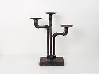 Full view of iron pipe candle holder showing three arms and base