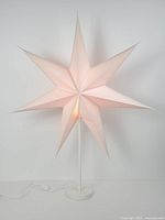 full view of lit white paper star table lamp on stand
