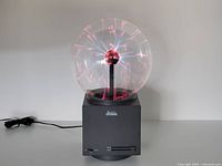 Plasma ball powered on showing red filaments and full unit