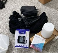 Overall view: boxed Cazon BP monitor, diffuser on cardboard box, quick start guide, two black bags, clear measuring cup