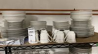 Overall view showing multiple stacks of plates, bowls and teacups on shelf