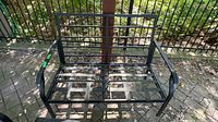 Front view of black metal loveseat frame showing overall structure and missing cushions