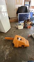 Chainsaw in closed orange hard case on garage floor