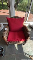 Front view showing woven rattan armchair and red cushions