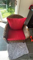 Front view of wicker armchair with red cushions