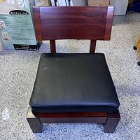 Front view of walnut low lounge chair with black leather cushion