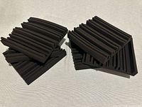 Six black acoustic foam panels stacked on fabric surface