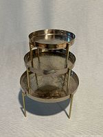 Three graduated metal display platters stacked to show size difference and dual-tone finish