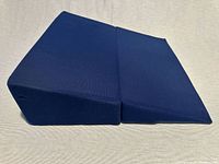 Navy blue folding foam wedge pillow shown unfolded, displaying wedge profile and fabric cover