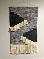 Front view of woven wall hanging showing full design, fringe, and dowel mount