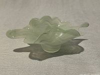 Side view showing wavy rim and elongated point of the light green swirl crystal bowl