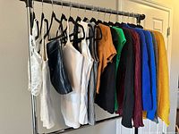 Full rack showing 16 assorted tops on hangers