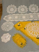Group shot showing all lace doilies, runner, yellow cloth and coasters