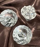 Two faceted crystal paperweights and crystal cake on fabric backdrop