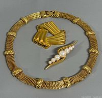 All three jewellery items laid out: necklace and two brooches