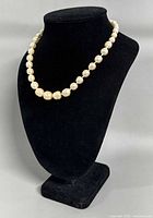 Necklace displayed on black bust showing overall length and pearl appearance