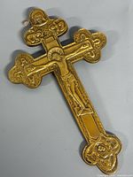 Front view of gold-tone metal Orthodox crucifix showing relief details