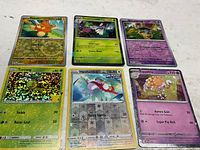 Photo of six Pokémon cards laid out in two rows showing fronts and foil patterns