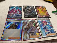 All six holographic Pokémon cards laid out, three Pokémon V and three Trainer full-art cards visible
