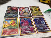 Overview of six holographic Pokémon cards in sleeves/toploaders on tabletop