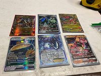 All six holographic Pokémon cards laid out in sleeves on tabletop