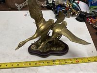 full view of brass two-geese sculpture with measuring tape for scale