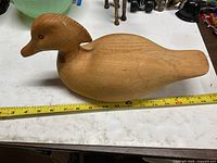 Top-side view of full wooden duck decoy next to measuring tape