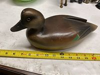 Left side view of wooden duck decoy with measuring tape