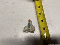 front view of ceramic gnome riding pig with tape measure for scale