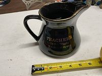 Left side view showing handle, logo text and tape for scale