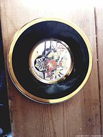 Top view of the decorative plate showing black band, gold rim and central chokin floral/cart design