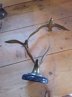 Sculpture lying on side showing three brass birds and marble base