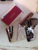 Group of vintage desk accessories including stapler, sharpener, pens, letter opener, memo book, tin and ink bottle