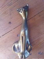 Full view of elongated brass cat figurine standing upright