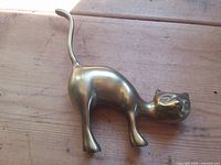 Full view brass cat figurine on wood surface