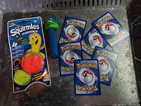 Sealed Squirmles toy, TMNT PEZ dispenser and seven Pokémon cards displayed
